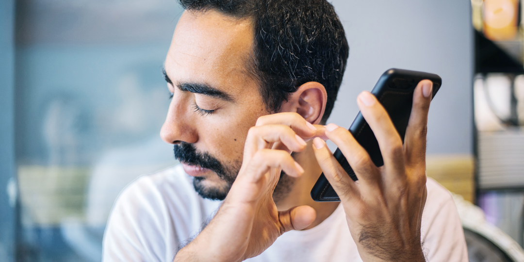 man met gesloten ogen houdt een telefoon bij zijn oor