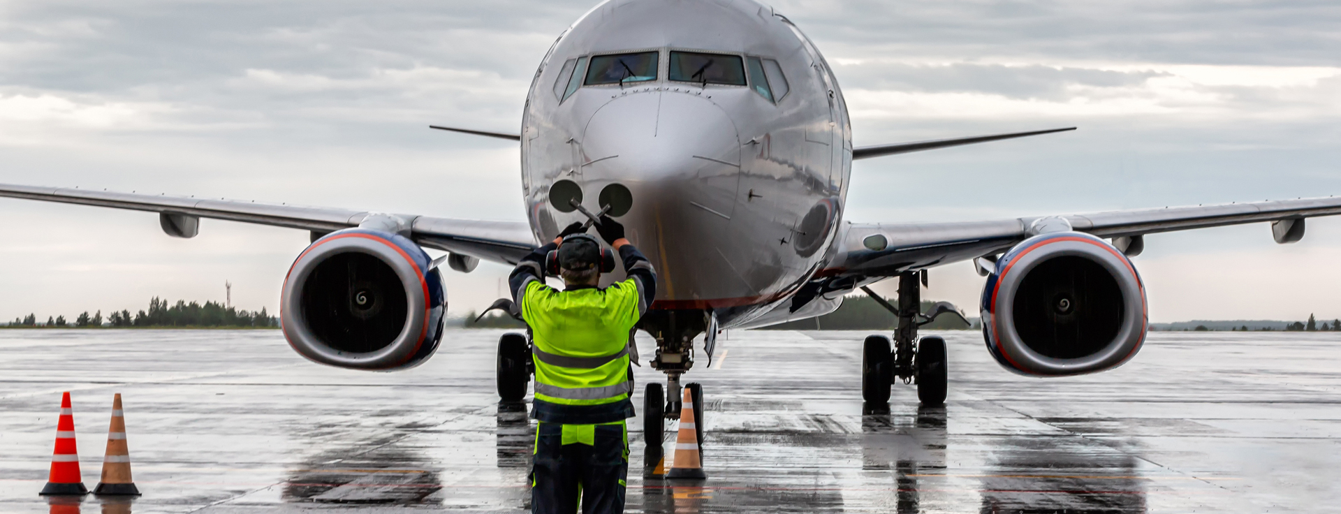 Person weist Flugzeug mit Handzeichen am Flughafen ein