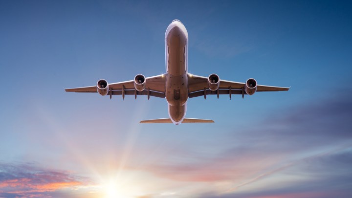Flugzeug liegt über Wolken bei Sonnenuntergang