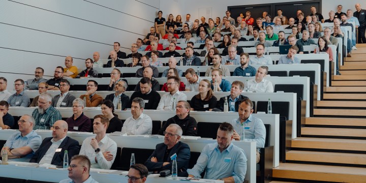 Personen im modernen Hörsaal folgen aufmerksam einer Präsentation