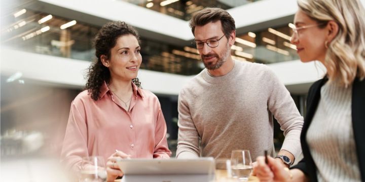 Personengruppe an einem Stehtisch im Gespräch in einem modernen Bürogebäude