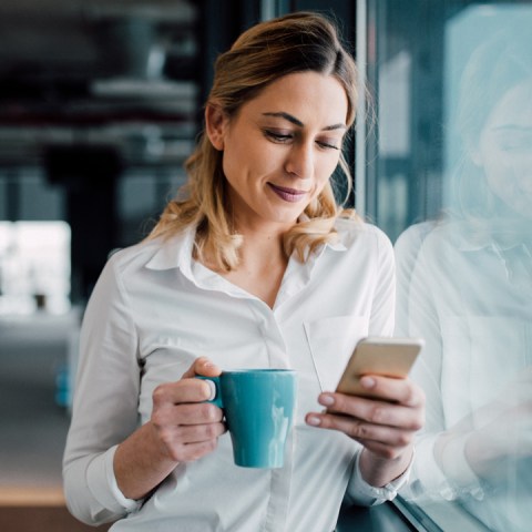 Une femme est assise et regarde sa tablette en souriant