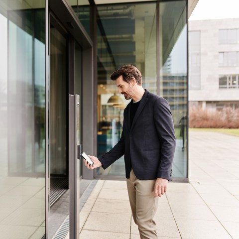 Un homme utilise son smartphone pour ouvrir la porte du terminal d'accès d'Interflex, la "Key-App"