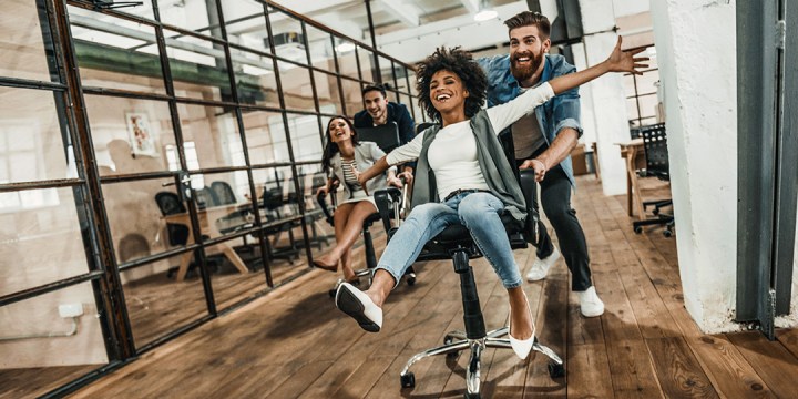 Glückliche Mitarbeiter lachen gemeinsam im Büro