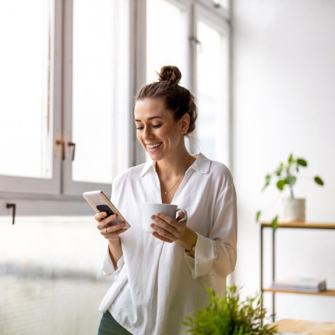 Frau blickt lächelnd auf Smartphone