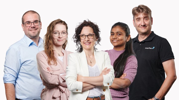 Callcenter-Mitarbeiter am Schreibtisch, blickt lachend auf den Monitor