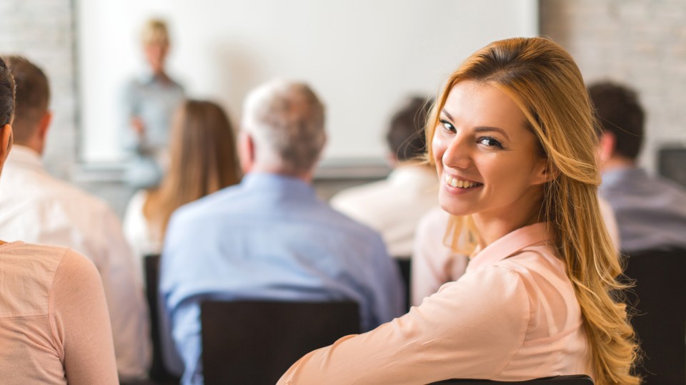 Woman during seminar turns to the viewer with a smile